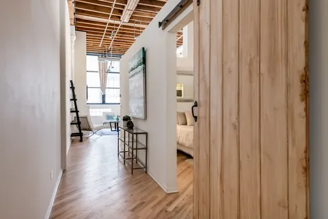 a view of a hallway with wooden floor and a living room