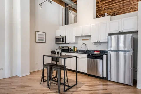 a kitchen with stainless steel appliances a refrigerator a stove a sink and white cabinets with wooden floor