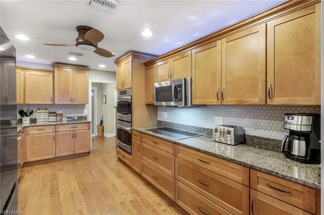 a kitchen with stainless steel appliances granite countertop a stove a sink dishwasher and a refrigerator with wooden floor