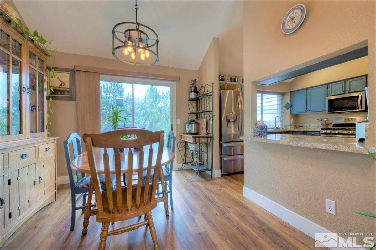 15135 Sylvester Road Reno, NV 89521 - Photo 7 of 34 a kitchen with stainless steel appliances granite countertop a stove a refrigerator a oven a sink a dining table and chairs with wooden floor