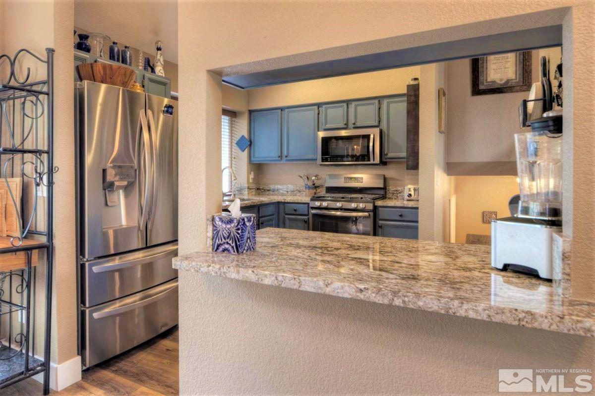 15135 Sylvester Road Reno, NV 89521 - Photo 8 of 34 a kitchen with stainless steel appliances granite countertop a refrigerator and a stove top oven