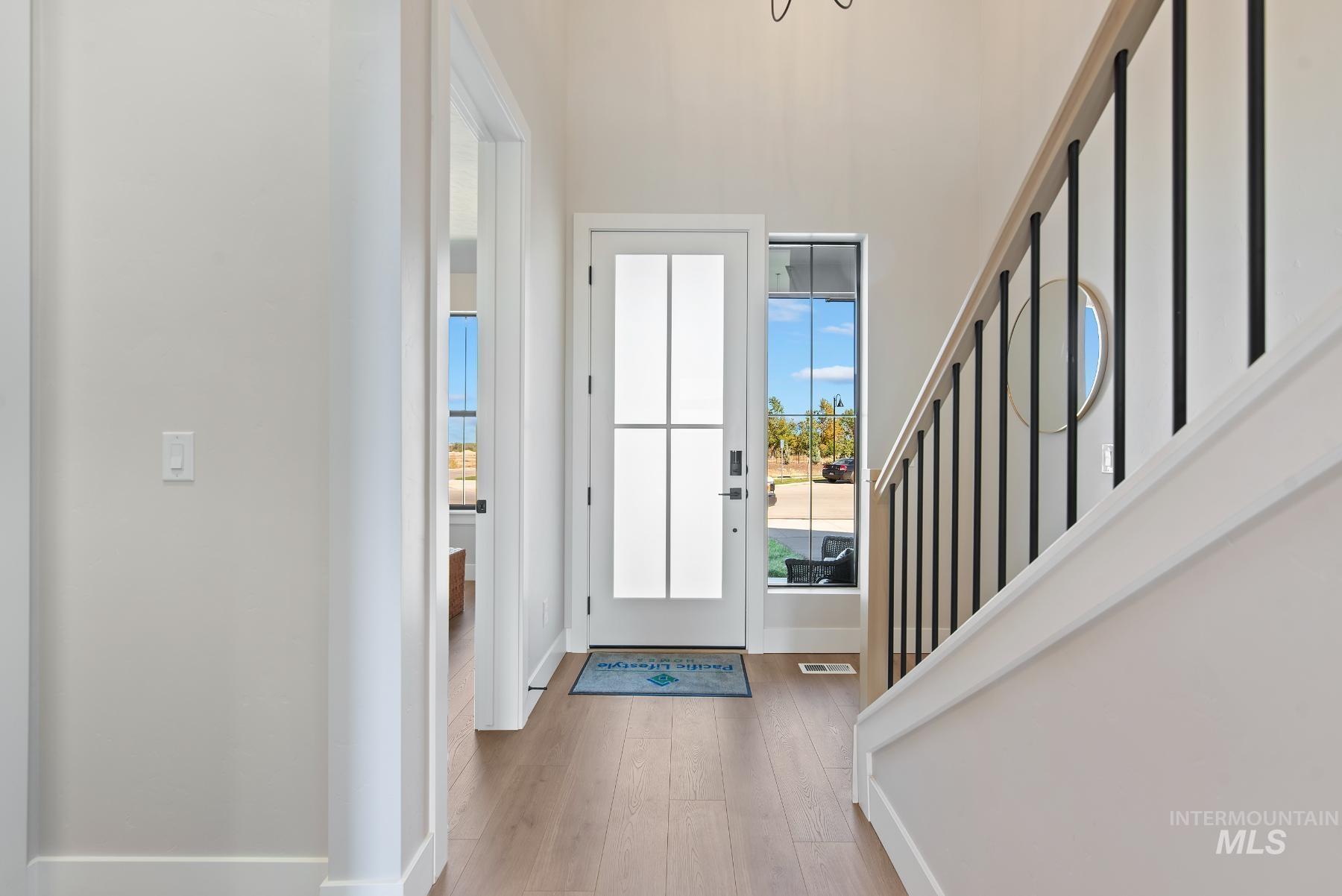 8410 West Graye Street, Unit ALPINE Meridian, ID 83646 - Photo 3 of 45 Open-concept living space featuring high ceilings, wood-finish flooring, a contemporary overhead railing, and a formal dining area with board and batten accent wall