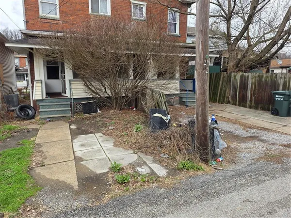 a view of a brick house with a yard and large tree