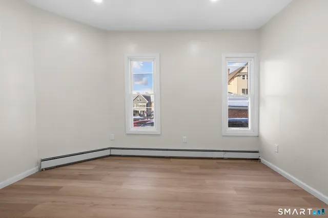 a view of an empty room with wooden floor and a window