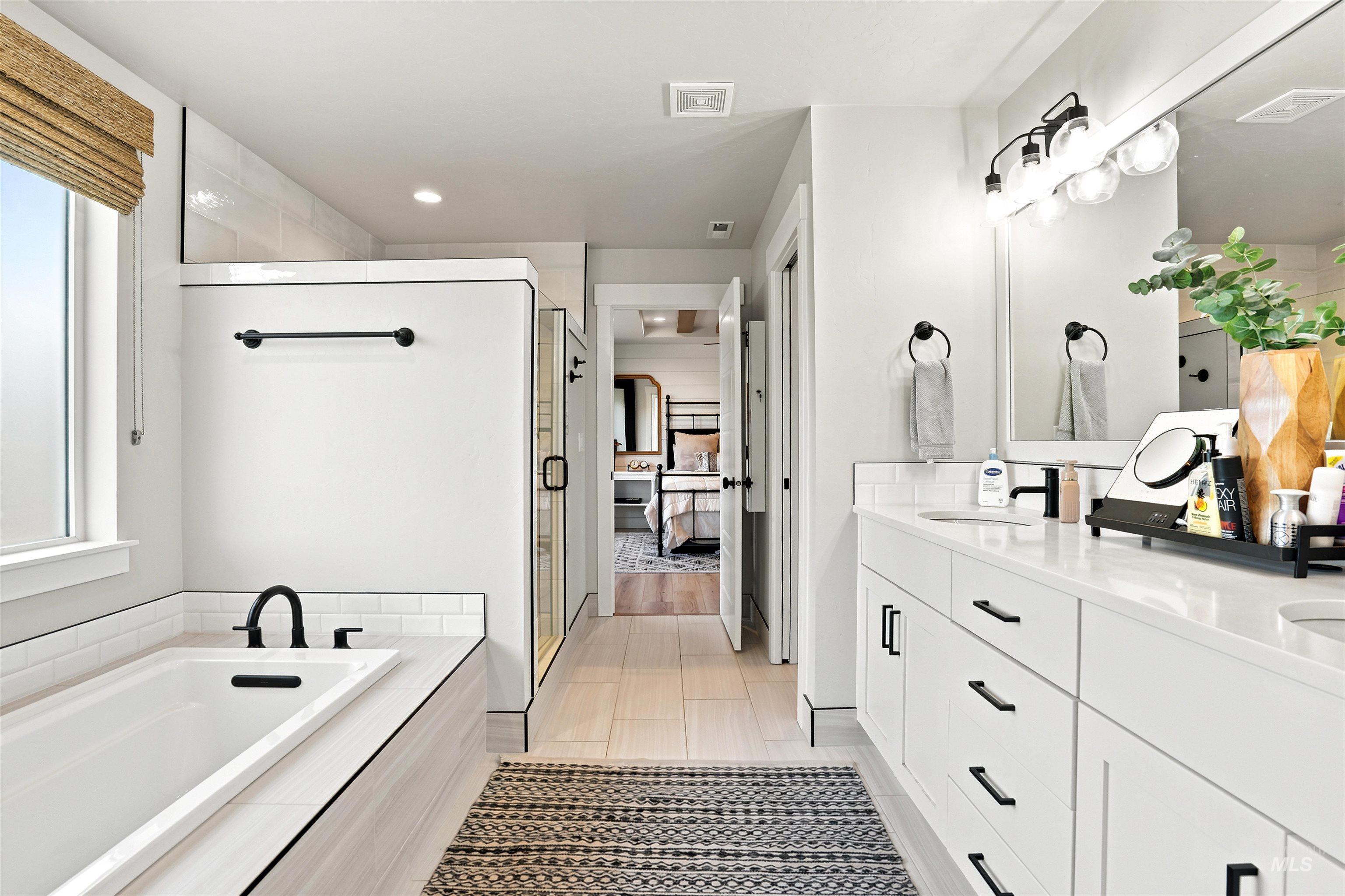 4323 West Ladle Rpds Drive Meridian, ID 83646 - Photo 19 of 49 Contemporary bathroom featuring a built-in soaking tub with matte black fixtures, a walk-in shower with clear glass enclosure, and a double vanity with ample storage