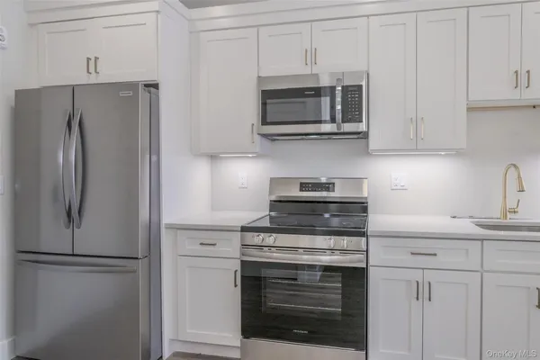 a kitchen with stainless steel appliances white cabinets white stove a microwave and a refrigerator