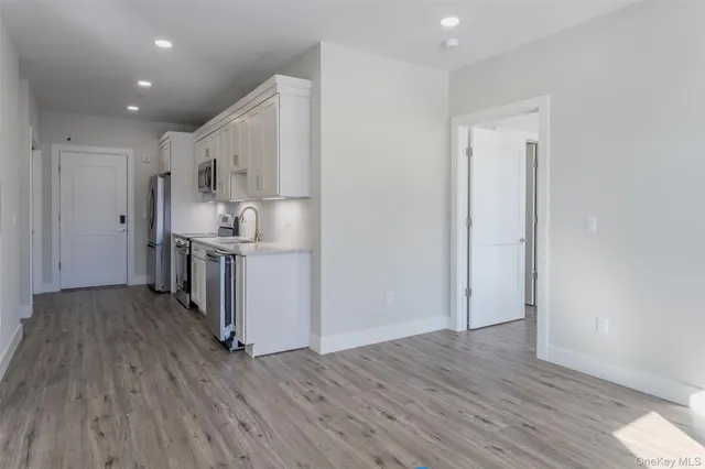 a view of kitchen with wooden floor electronic appliances and cabinets