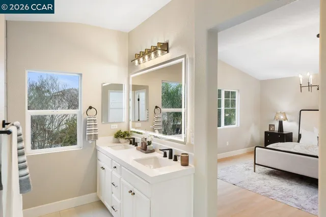 a en suite bathroom with a double vanity sink large mirror and a window