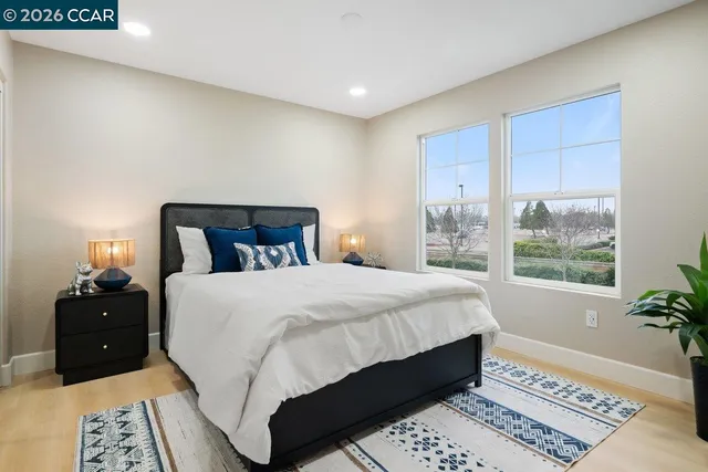 a bedroom with a large bed and a lamp on dresser