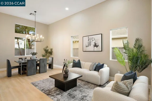 a living room with furniture kitchen view and a chandelier