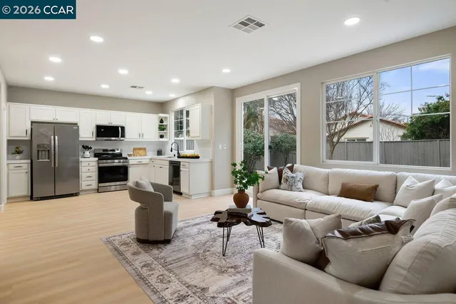 a living room filled with furniture and kitchen view