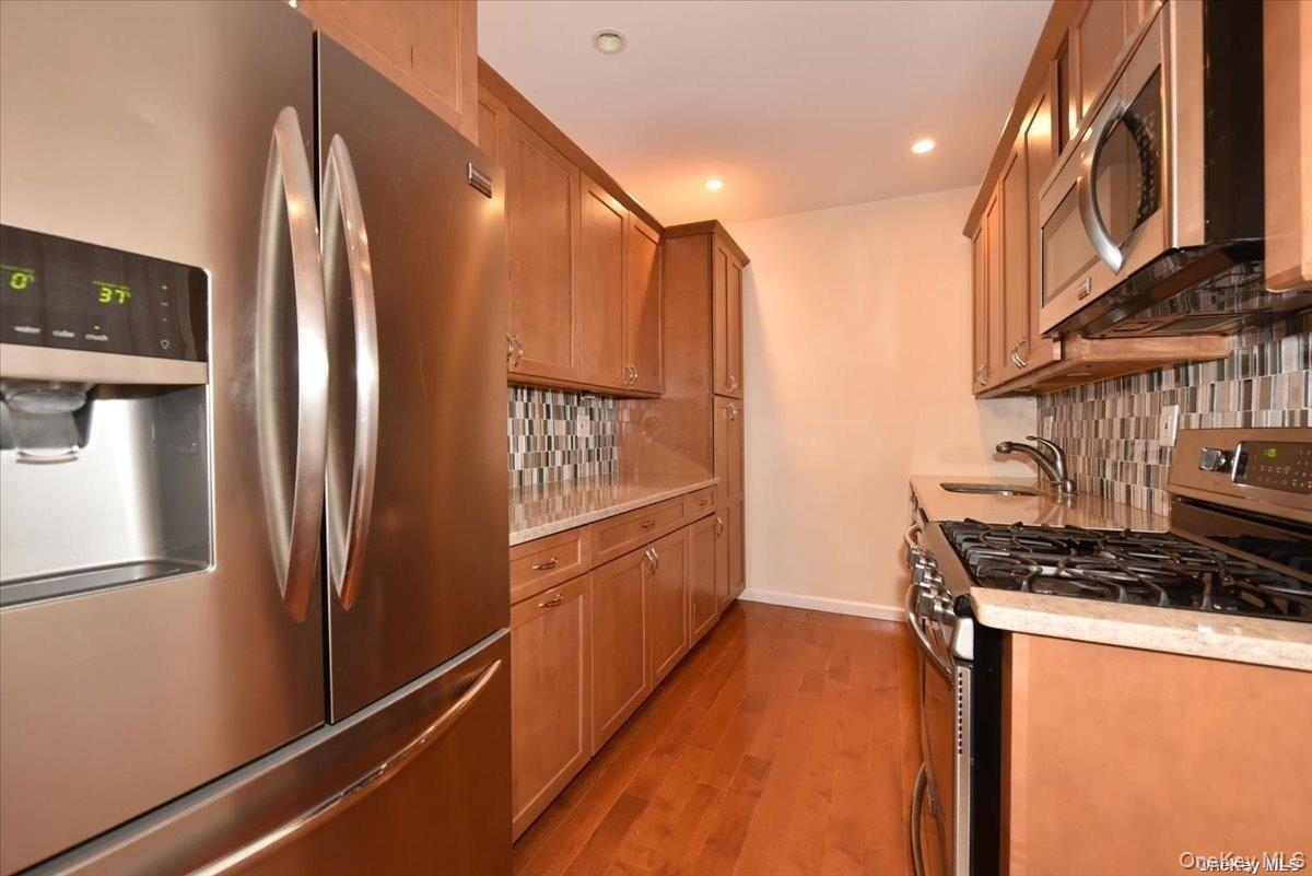 175-06 Devonshire Road, Unit 1J Queens, NY 11432 - Photo 9 of 20 a kitchen with stainless steel appliances a refrigerator and a stove