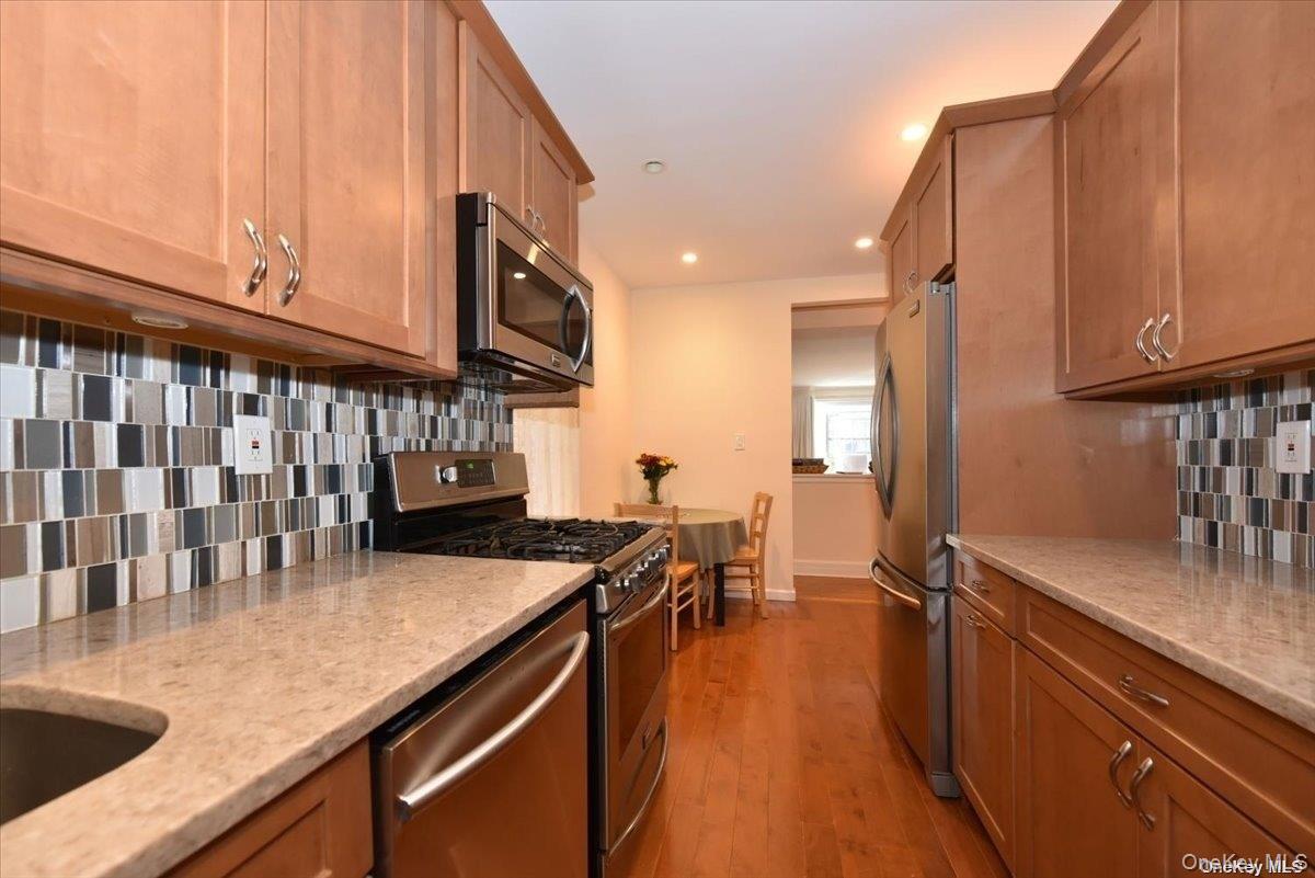 175-06 Devonshire Road, Unit 1J Queens, NY 11432 - Photo 10 of 20 a kitchen with stainless steel appliances granite countertop a sink a stove counter space and cabinets