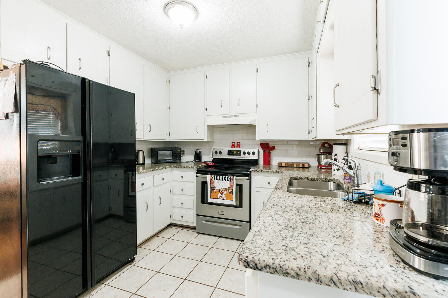 1907 73rd Street Lubbock, TX 79423 - Photo 16 of 41 a kitchen with granite countertop a refrigerator and a stove top oven