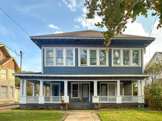 a view of a white house with a large windows and a yard with palm trees