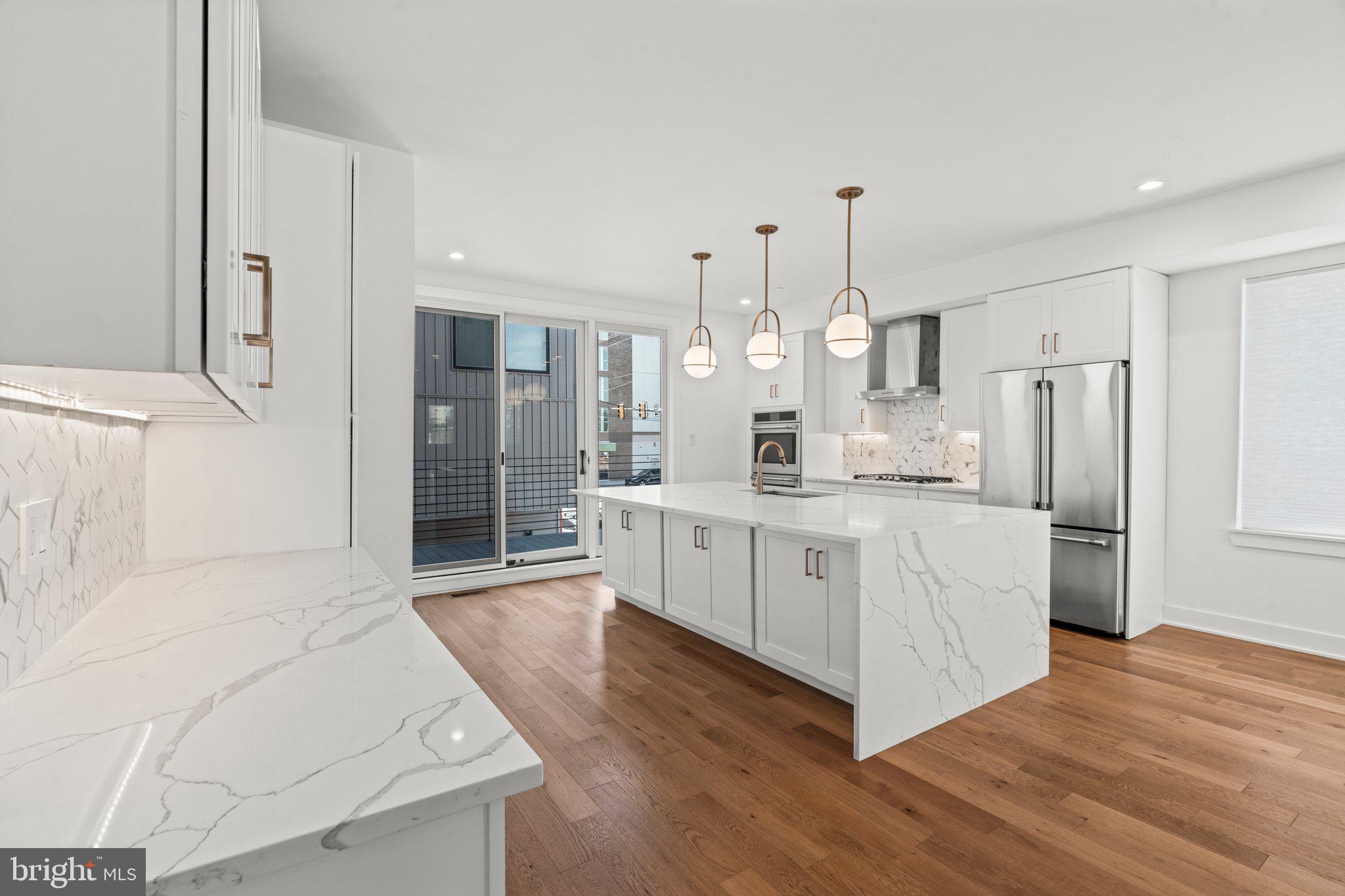 2240 League Street Philadelphia, PA 19146 - Photo 6 of 43 a large white kitchen with cabinets a island a refrigerator a stove a sink cabinets and wooden floor