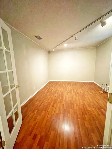 a view of empty room with wooden floor and fan