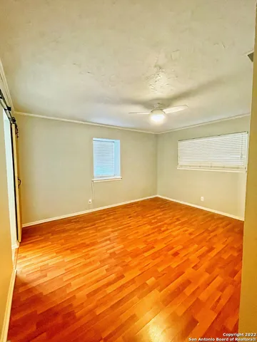 a view of empty room with wooden floor and fan