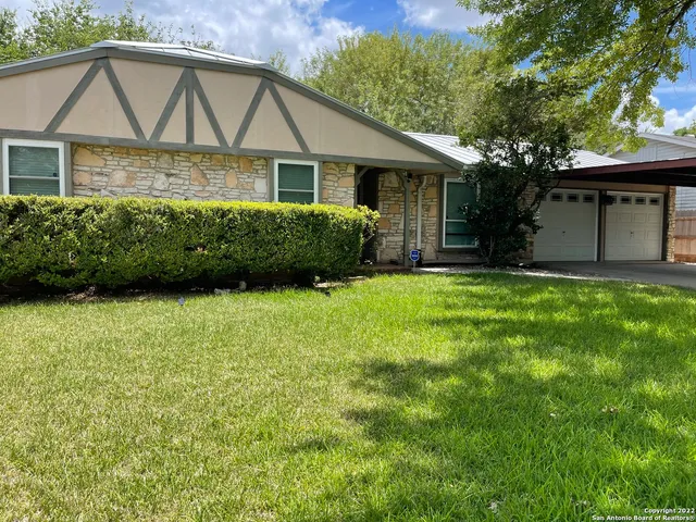 a view of a white house with a big yard and potted plants