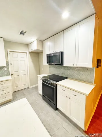 a kitchen with stainless steel appliances granite countertop a stove a sink and a microwave