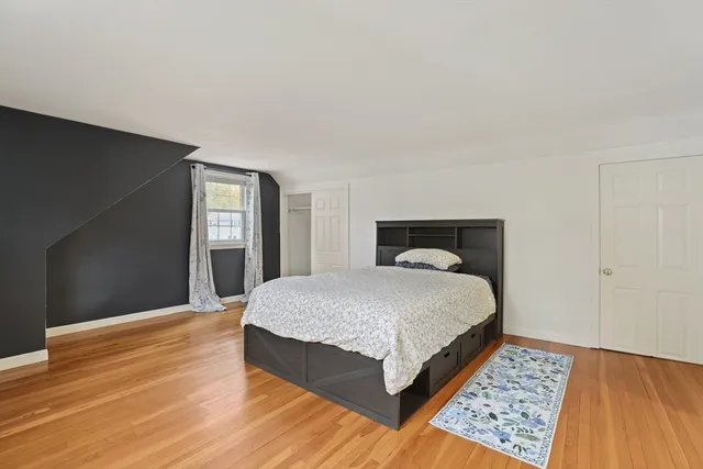 a spacious bedroom with a bed and wooden floor