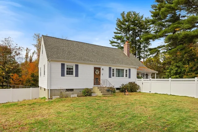 a front view of house with yard and trees in the background