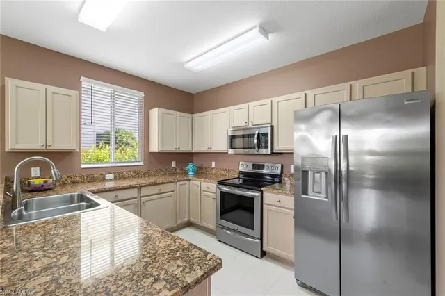 a kitchen with granite countertop a sink stainless steel appliances and a window