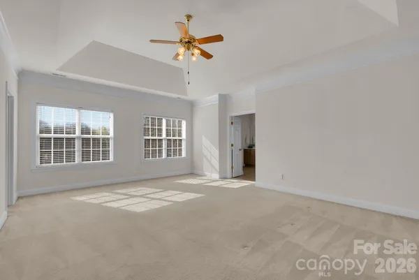 a spacious bedroom with a large bed chandelier and a window