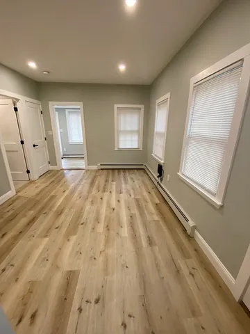 an empty room with wooden floor and windows
