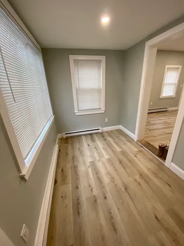 a view of an empty room with wooden floor and a window