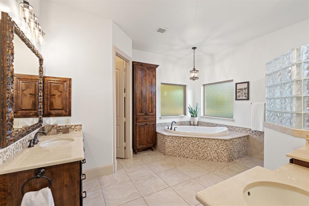 3108 Jenbri Street Flower Mound, TX 75022 - Photo 18 of 39 This luxurious primary bath features two spacious vanities with marble counters - one with a dedicated sit-down makeup area for added convenience. To complete the space, a custom linen cabinet provides additional storage along with an overhead cabinet in the enclosed water closet.