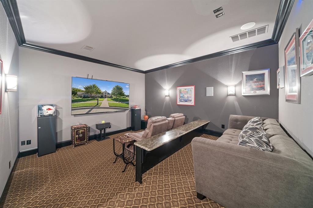 3108 Jenbri Street Flower Mound, TX 75022 - Photo 23 of 39 Conveniently located media room sits thoughtfully between the kitchen area and garage. Movie nights are enhanced by the 98" 4K screen TV, tower speakers and tiered seating with granite drink counter for ease of those late night movie snacks! Just outside in the hall is a closet for the media equipment.