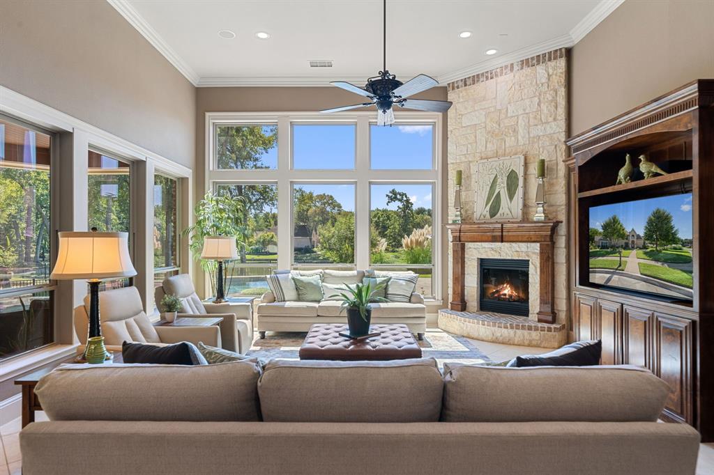 3108 Jenbri Street Flower Mound, TX 75022 - Photo 9 of 39 A cozy stone fireplace accents the great room, perfect for family gatherings including a rich wood built-in cabinet providing ample TV space and storage. Through the expansive windows, the views unfold of the sparking pool and spa then extending beyond to the adjacent peaceful community pond with fountain. Just steps away is the central powder bath.