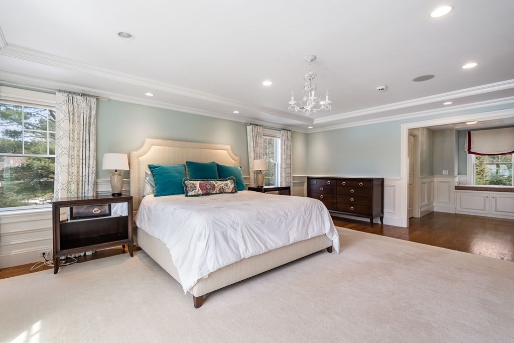 55 Edmunds Road Wellesley, MA 02481 - Photo 23 of 40 a spacious bedroom with a bed and a chandelier