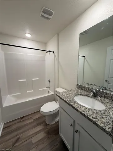 a bathroom with a granite countertop sink toilet a mirror and bathtub
