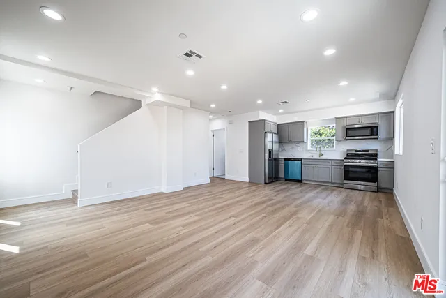 a view of kitchen with kitchen island granite countertop wooden floor stainless steel appliances and cabinets