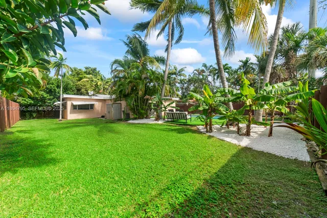 a backyard of a house with table and chairs plants and large tree