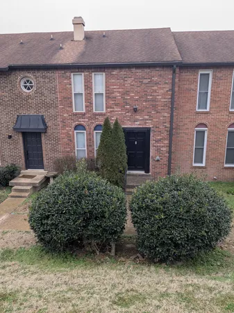 a view of a brick house next to a yard