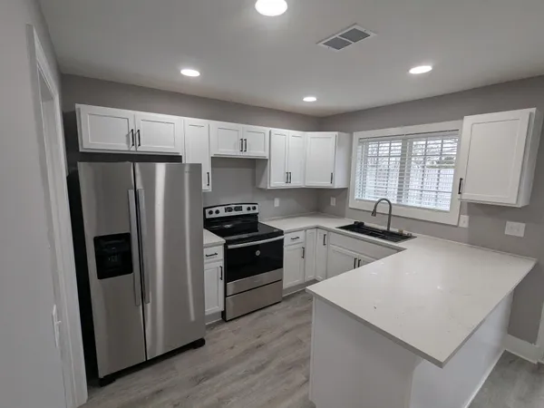 a kitchen with a refrigerator a sink stainless steel appliances cabinets and a window