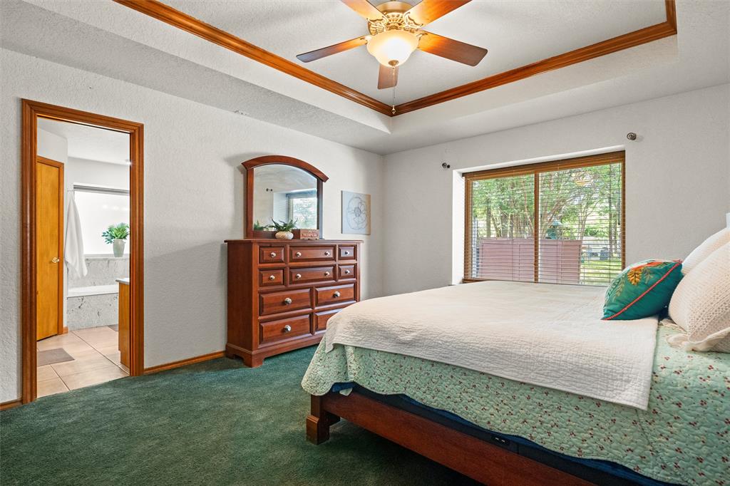 217 Valley Ranch Road Weatherford, TX 76087 - Photo 22 of 38 Bedroom featuring a tray ceiling with wood trim, a ceiling fan, and a large window with blinds