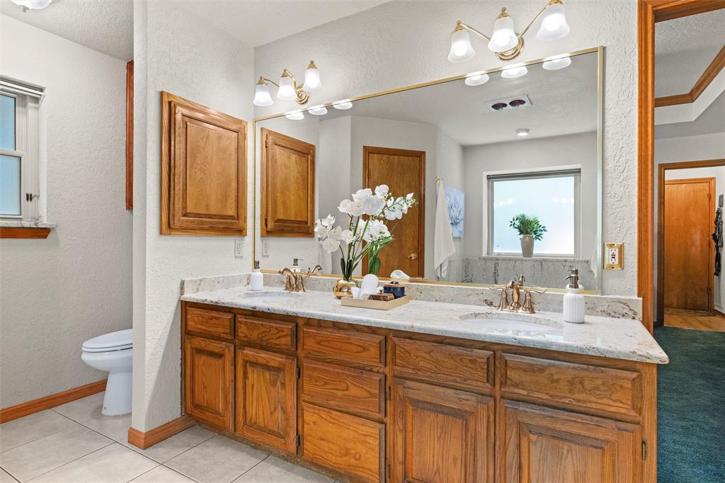 217 Valley Ranch Road Weatherford, TX 76087 - Photo 23 of 38 Double vanity featuring wood cabinetry, integrated sinks, and a stone-finish countertop