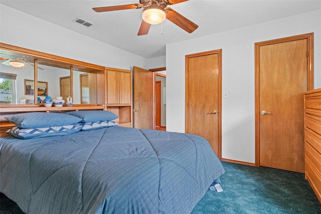 217 Valley Ranch Road Weatherford, TX 76087 - Photo 29 of 38 Bedroom featuring wood-finish doors, built-in wooden headboard with mirrored panels and integrated shelving, white walls, and a ceiling fan with light fixture