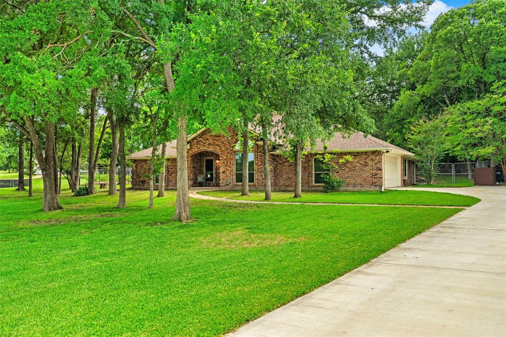 217 Valley Ranch Road Weatherford, TX 76087 - Photo 4 of 38 Brick exterior residence with an arched entry, a two-car garage, and mature trees encompassing the property
