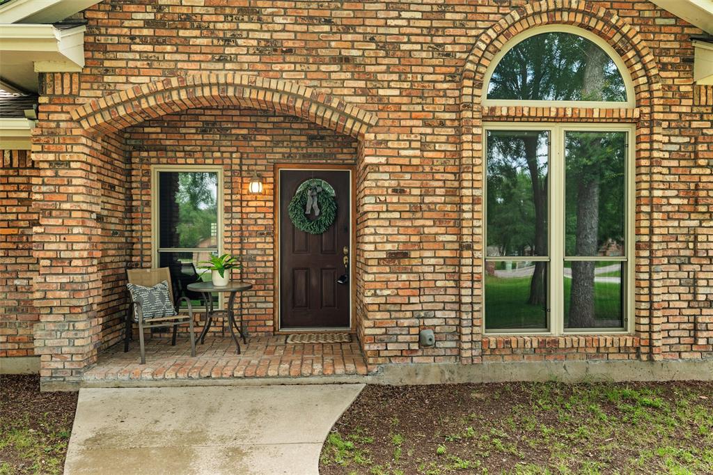 217 Valley Ranch Road Weatherford, TX 76087 - Photo 5 of 38 Brick exterior featuring an arched entryway, a solid wood front door, and a multi-pane window with an arched transom
