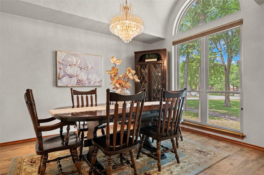 217 Valley Ranch Road Weatherford, TX 76087 - Photo 7 of 38 Dining area featuring a crystal chandelier, wood-finish flooring, and a large arched window