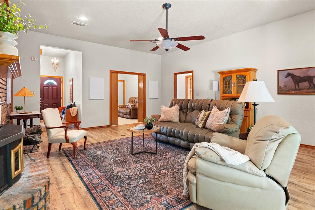217 Valley Ranch Road Weatherford, TX 76087 - Photo 8 of 38 Spacious living area featuring wood-finish flooring, a ceiling fan, and a brick fireplace