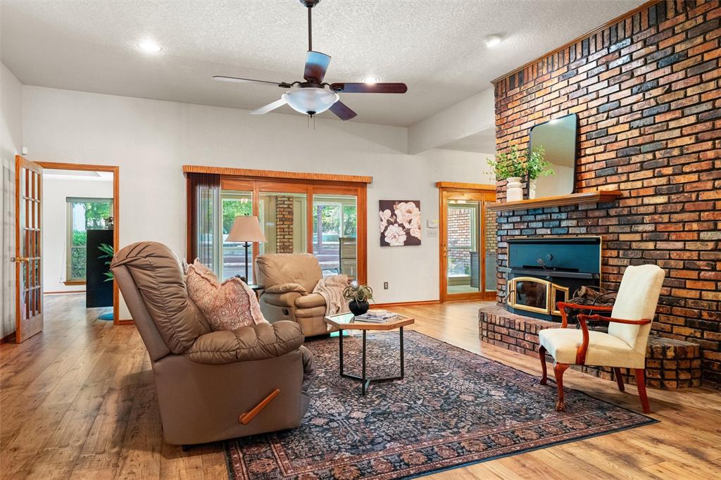 217 Valley Ranch Road Weatherford, TX 76087 - Photo 9 of 38 Spacious living area featuring a prominent brick fireplace with a wood-burning insert and a substantial wood mantel