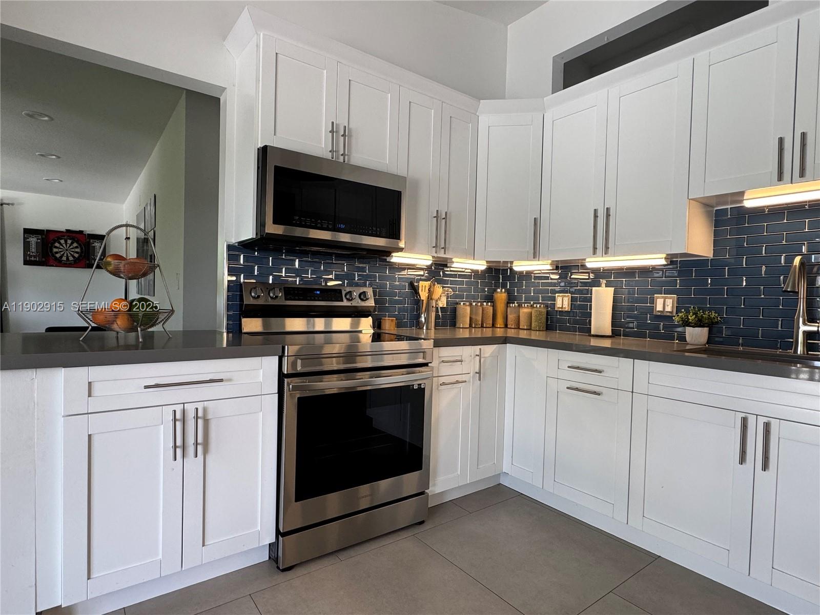 20440 Southwest 292nd Street Homestead, FL 33030 - Photo 39 of 57 a kitchen with white cabinets and stainless steel appliances