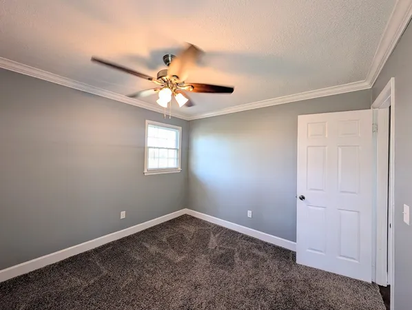 an empty room with a window and a fan