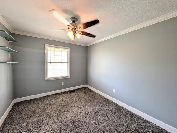 an empty room with windows and fan